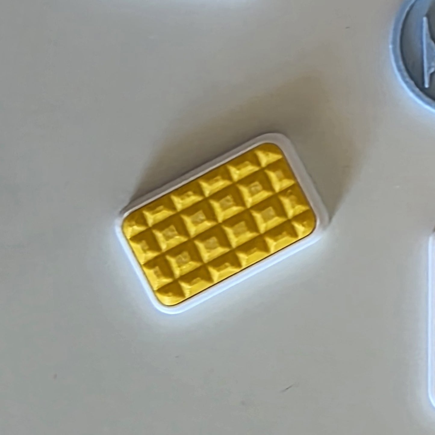 A small rectangular yellow textured item with a white border, photographed on a plain light surface.