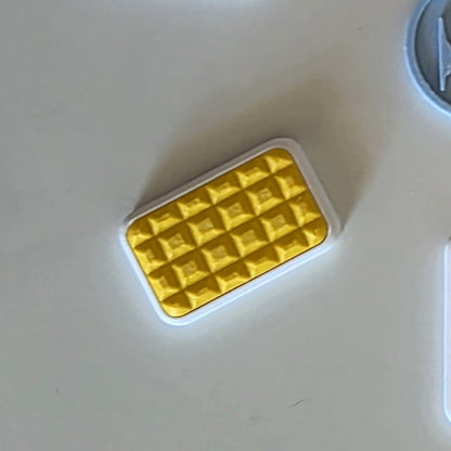 A small rectangular yellow textured item with a white border, photographed on a plain light surface.