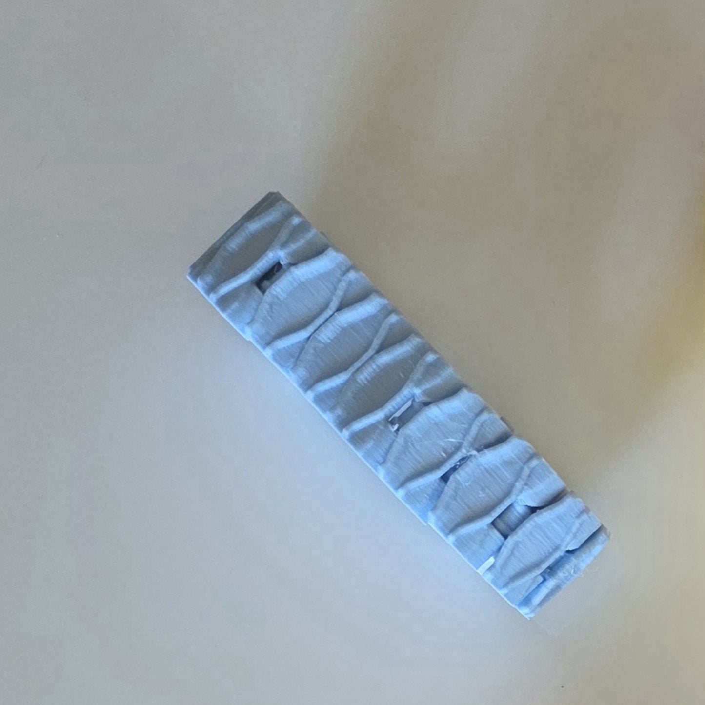 A light blue textured hair claw clip shown diagonally on a plain beige background.