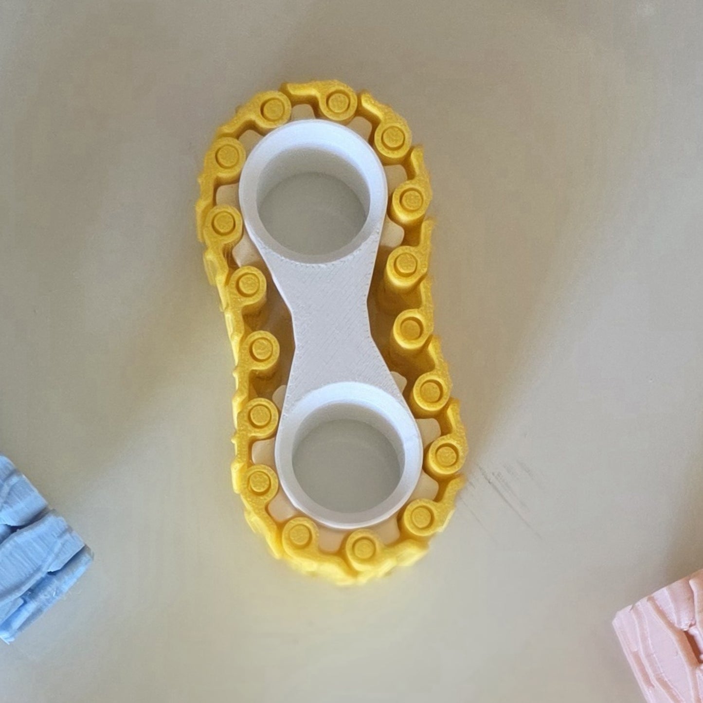 A yellow and white plastic baby foot stimulator toy placed on a light beige surface.