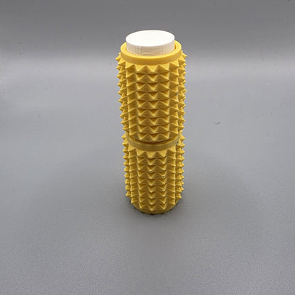 A yellow textured foam roller with a white cap, standing upright on a gray surface.