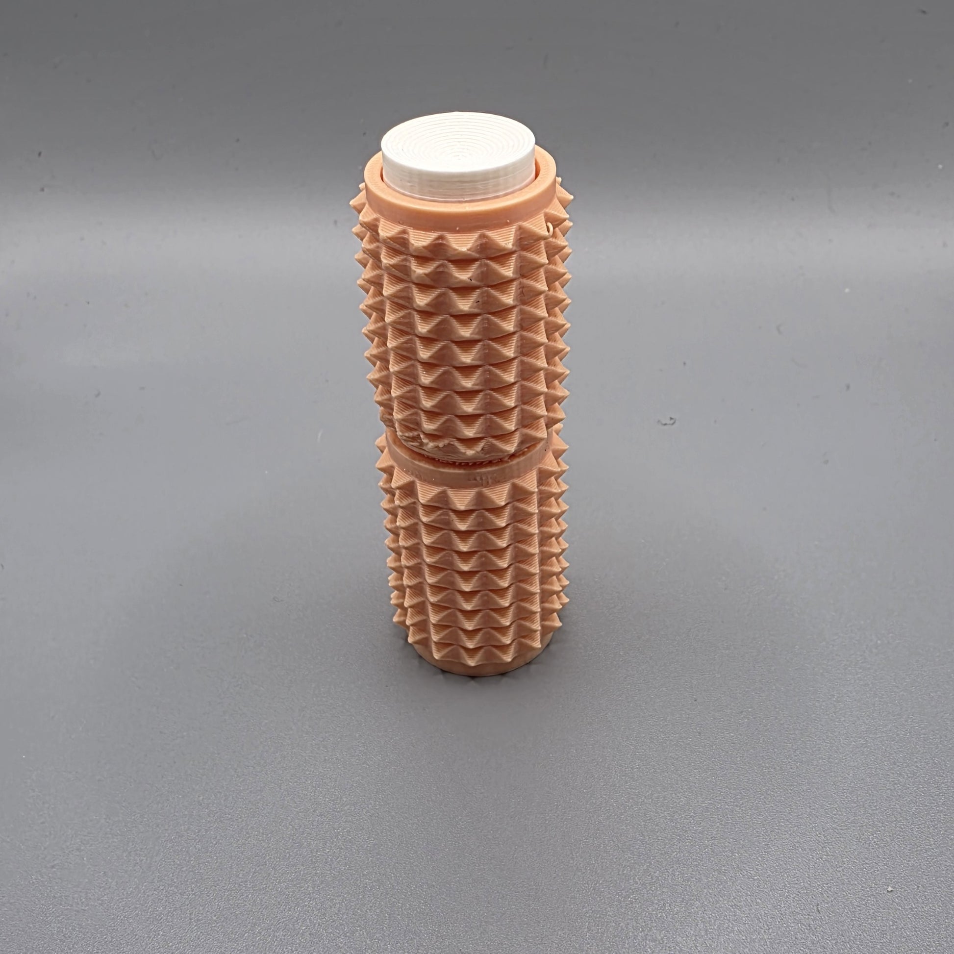 A textured, ribbed plastic cylindrical container with a white screw-on cap, standing upright on a neutral gray background.
