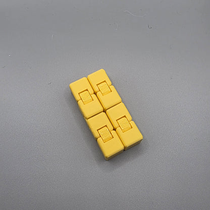 A small yellow plastic accessory made of six connected rectangular blocks with small sliding details, photographed on a plain gray surface.